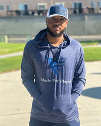 Man wearing a blue hoodie with a logo and text, standing outdoors.